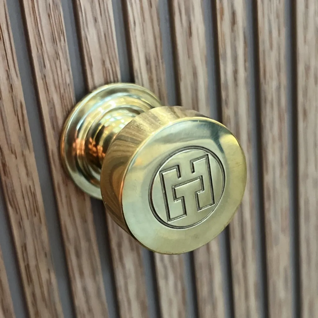 Hassel&Teudt HKN01L - Møbelhåndtak med H&T-logo, polert messing naturfarget