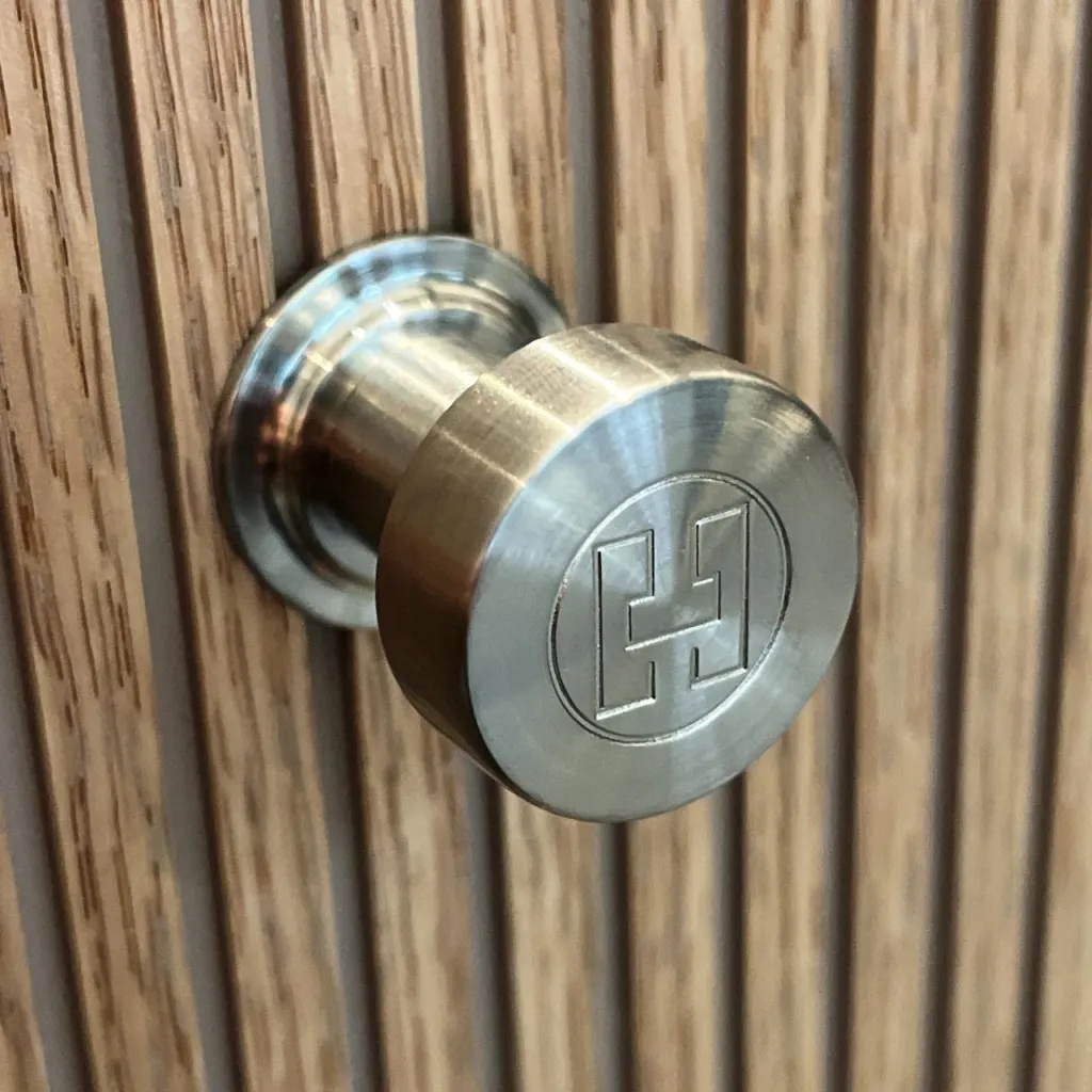 Hassel&Teudt HKN01L - Møbelhåndtak med H&T-logo, PVD-børstet stål